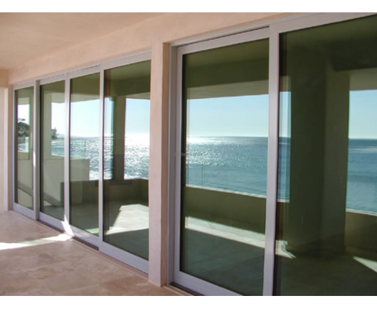 Bīdāmās ārdurvis izveidotas no alumīnija profiliem un stikla paketēm ēkas fasādē Bīdāmās ārdurvis izveidotas no alumīnija profiliem un stikla paketēm ēkas fasādē