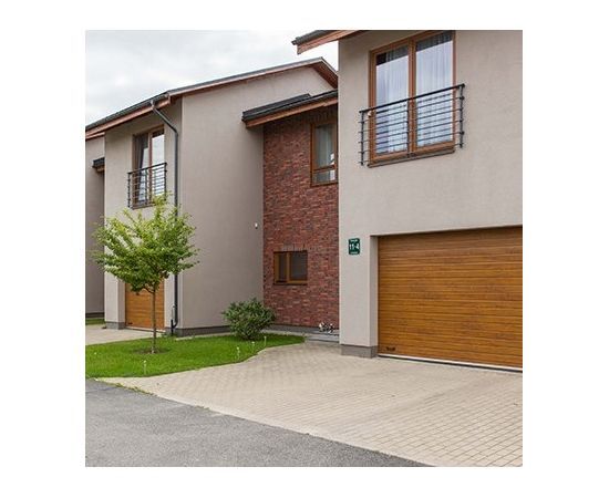 Privātmāja ar gaiši brūniem sekciju garāžu vārtiem, harmoniski saskaņotiem ar ēkas fasādi.