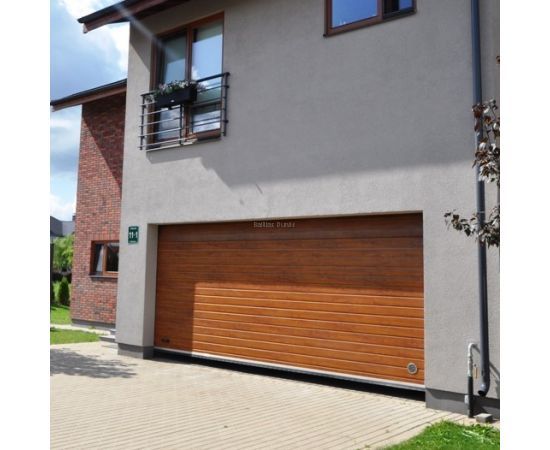 Privātmāja ar gaiši brūniem sekciju garāžu vārtiem, harmoniski saskaņotiem ar ēkas fasādi.